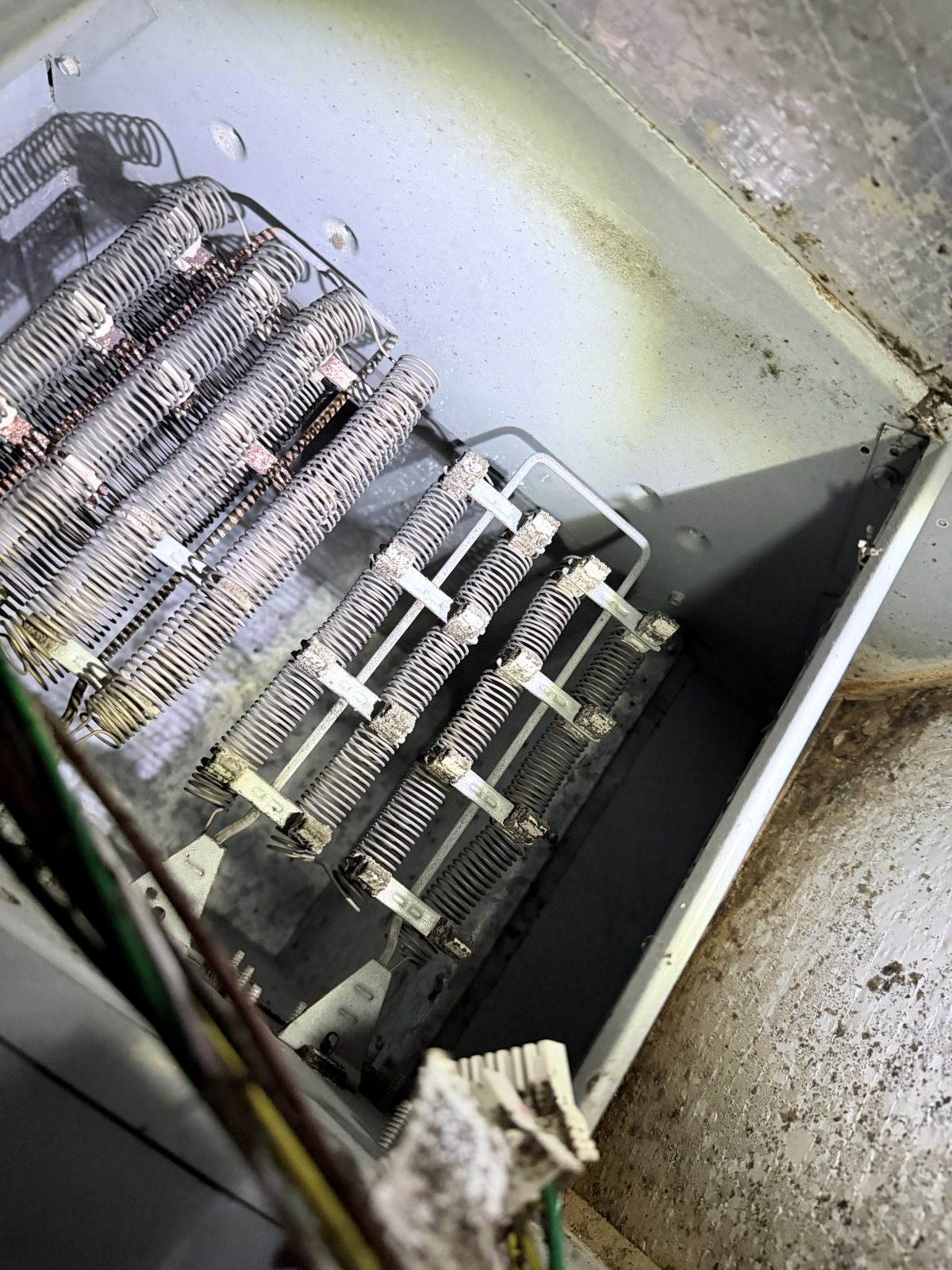 A close view inside metal HVAC equipment showing electric heating elements.